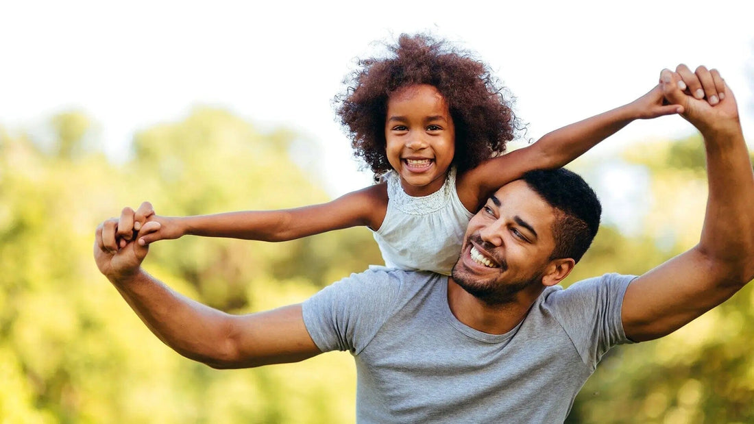 father giving child a piggy back outside