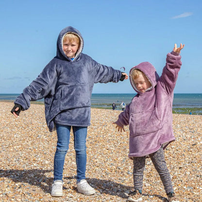 Two kids standing on a beach wearing Hooded Wearable Blanket