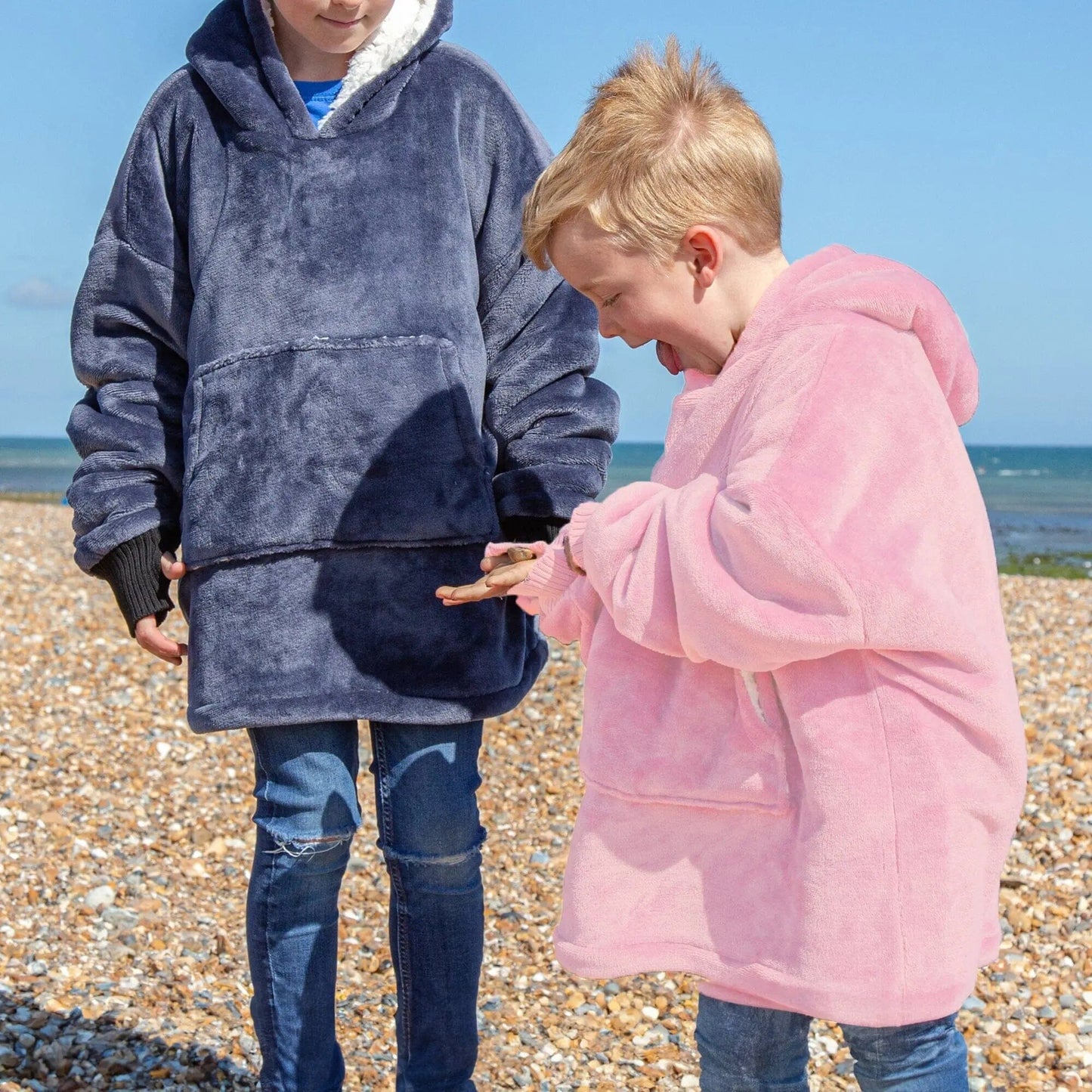 Two kids standing on a beach wearing Hooded Wearable Blanket