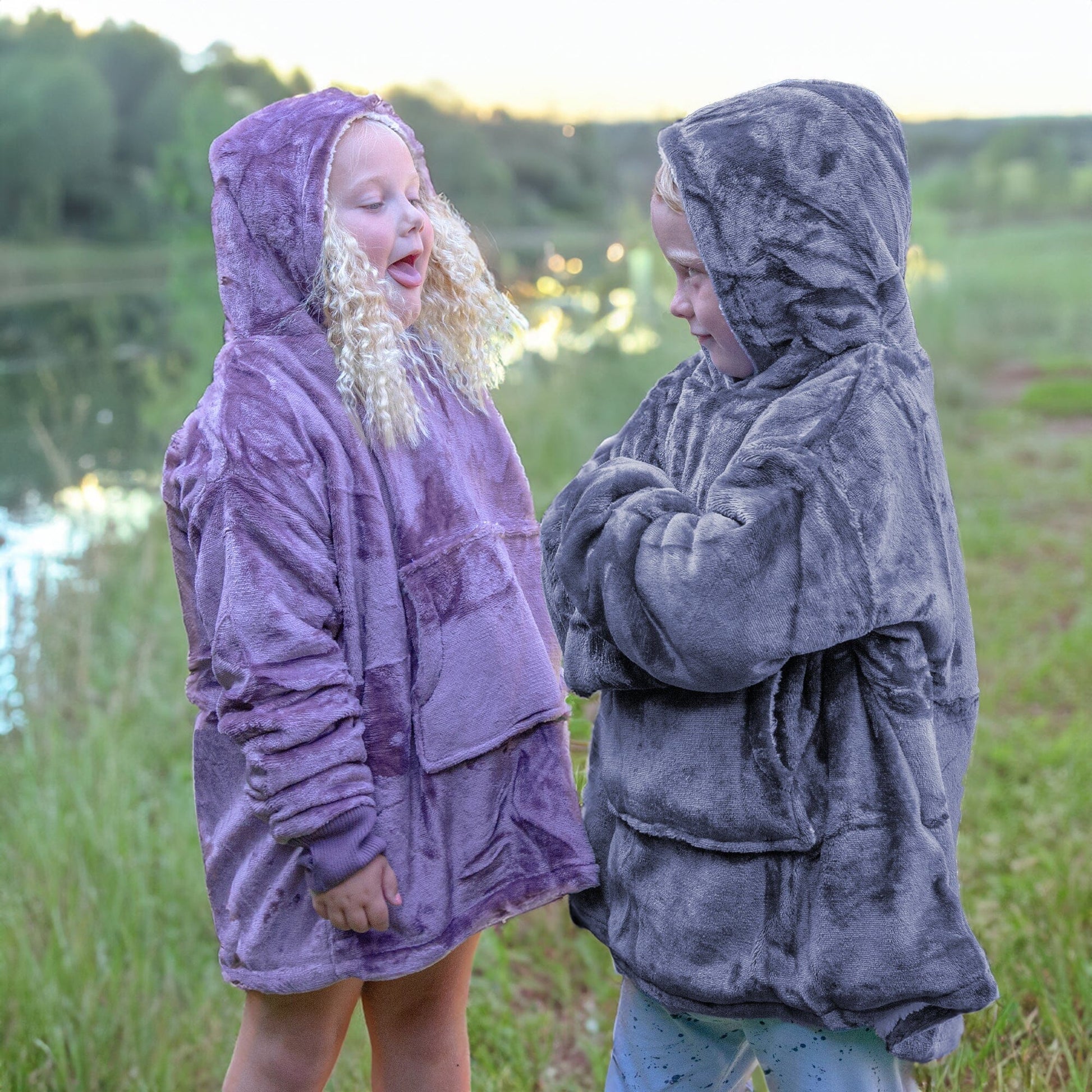 Two kids standing in a field wearing Hooded Wearable Blanket