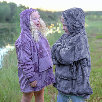 Two kids standing in a field wearing Hooded Wearable Blanket