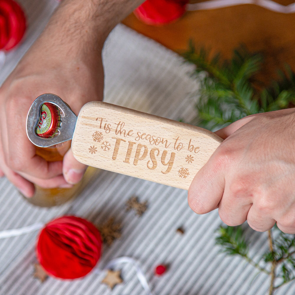Christmas Wooden Long Handled Bottle Opener opening a beer bottle with Christmas props around
