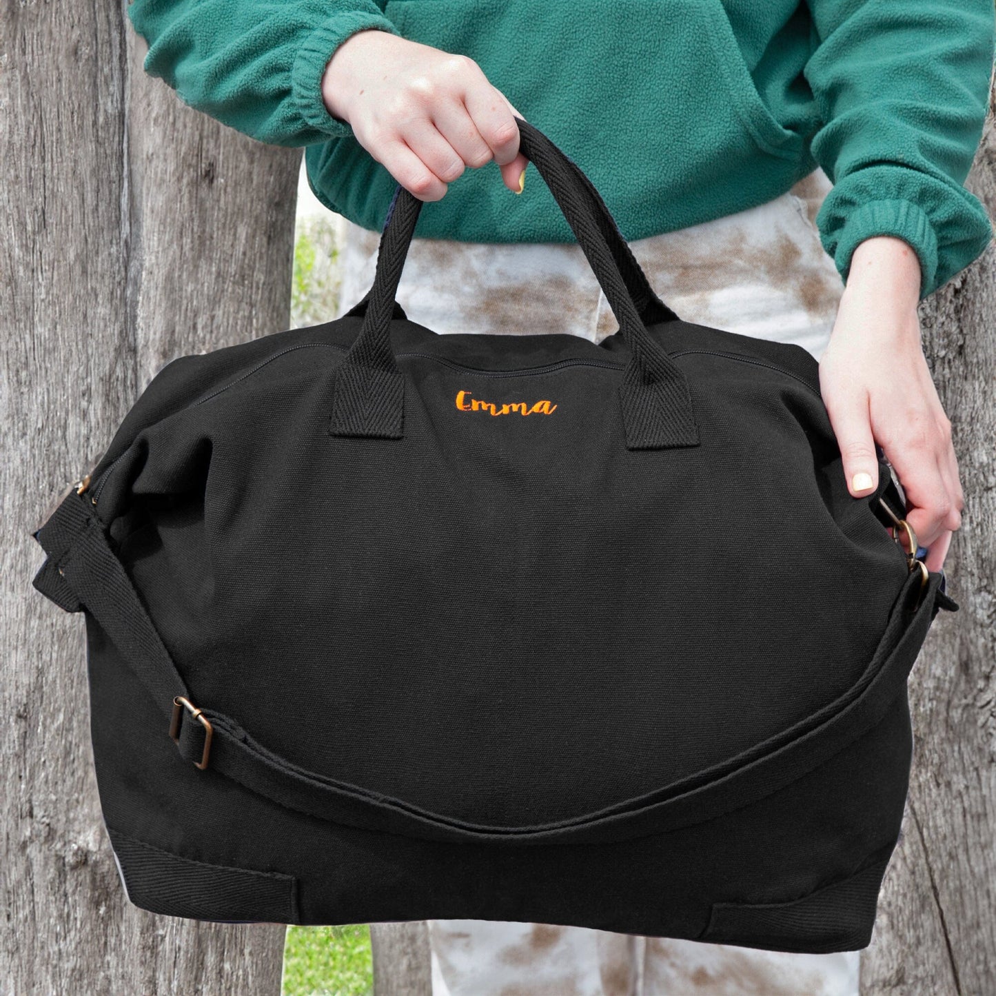 Outdoor scene of a woman carrying a black personalised recycled canvas bag