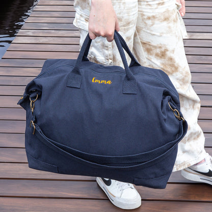 Outdoor scene of a woman carrying a navy personalised recycled canvas bag on a deck