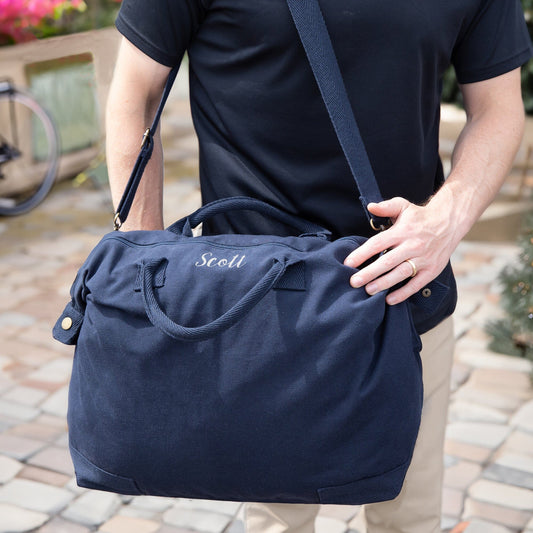 Outdoor scene of a man carrying a navy personalised recycled canvas bag