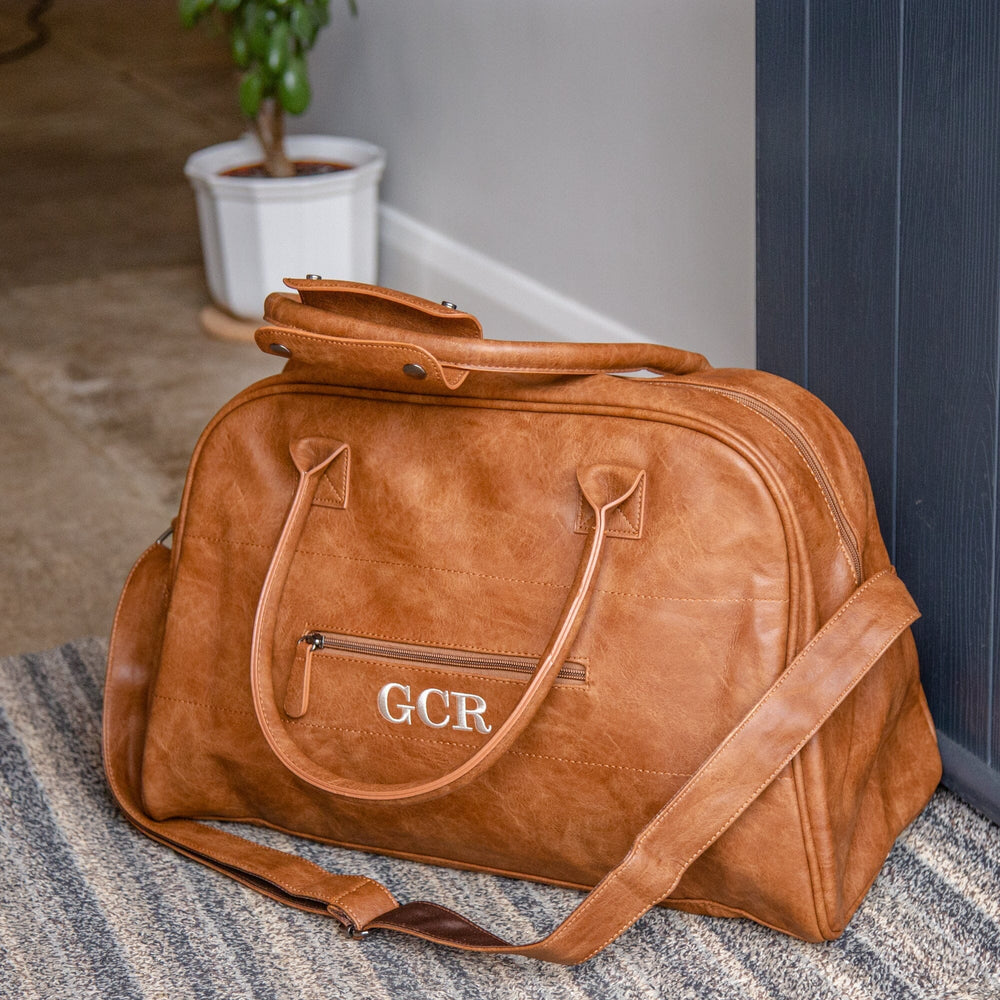 Faux Leather Overnight Bag In Brown next to the main door of a house