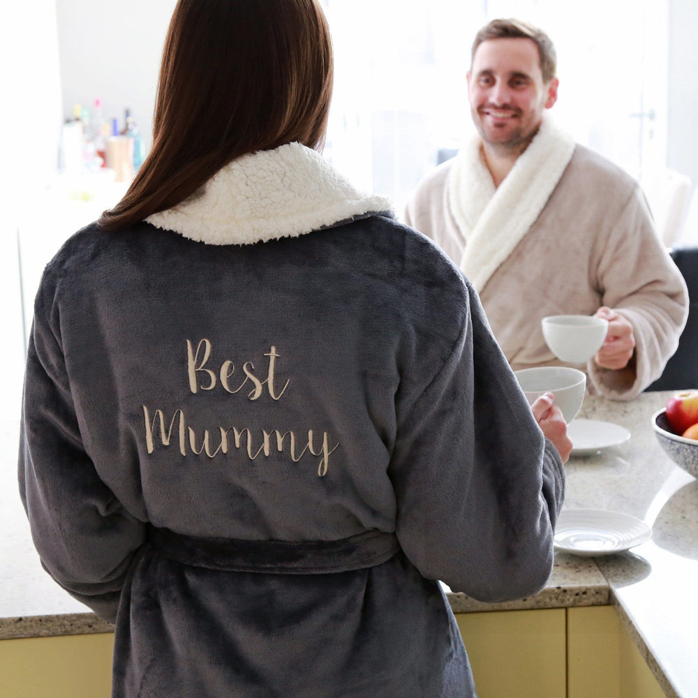 Female wearing a personalised sherpa robe with 'Best Mummy' text in a kitchen setting.