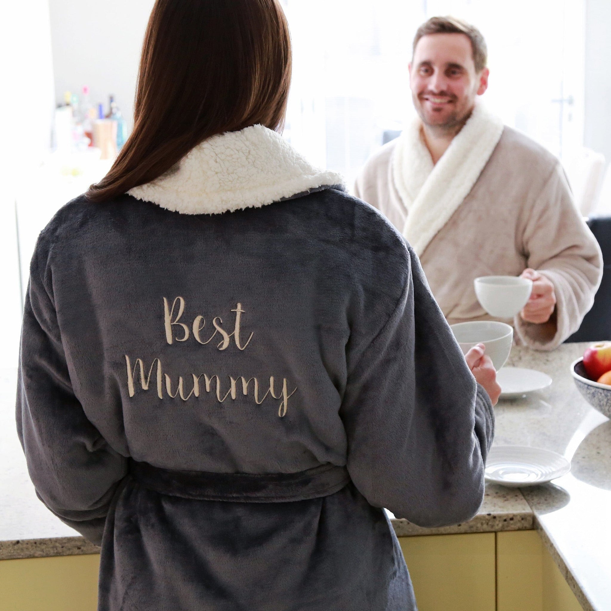Female wearing a personalised sherpa robe with 'Best Mummy' text in a kitchen setting.