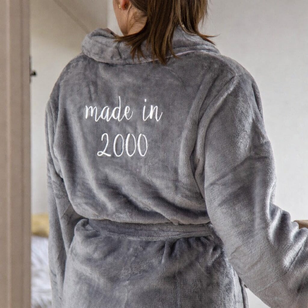 Person wearing a gray robe with 'made in 2000' text on the back.
