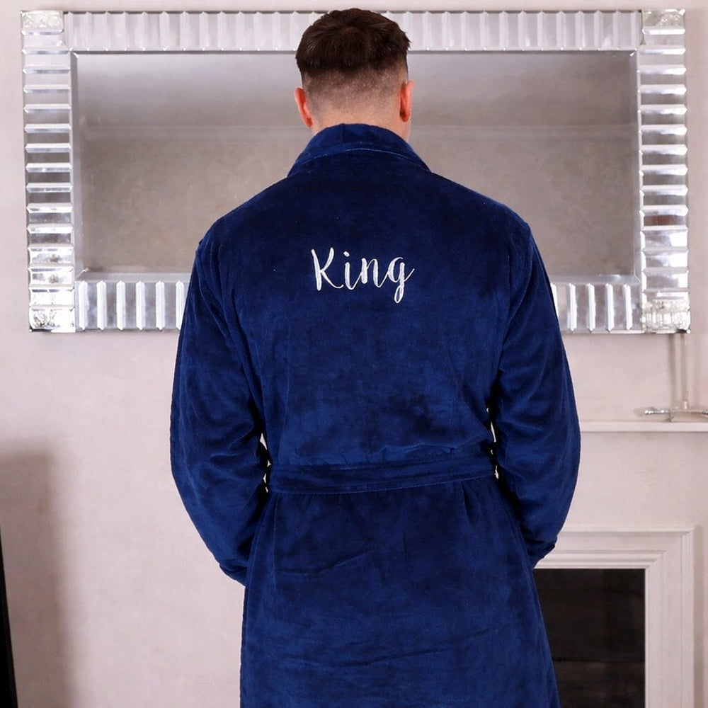 Man wearing a blue robe with 'King' embroidered on the back, standing in front of a mirror.