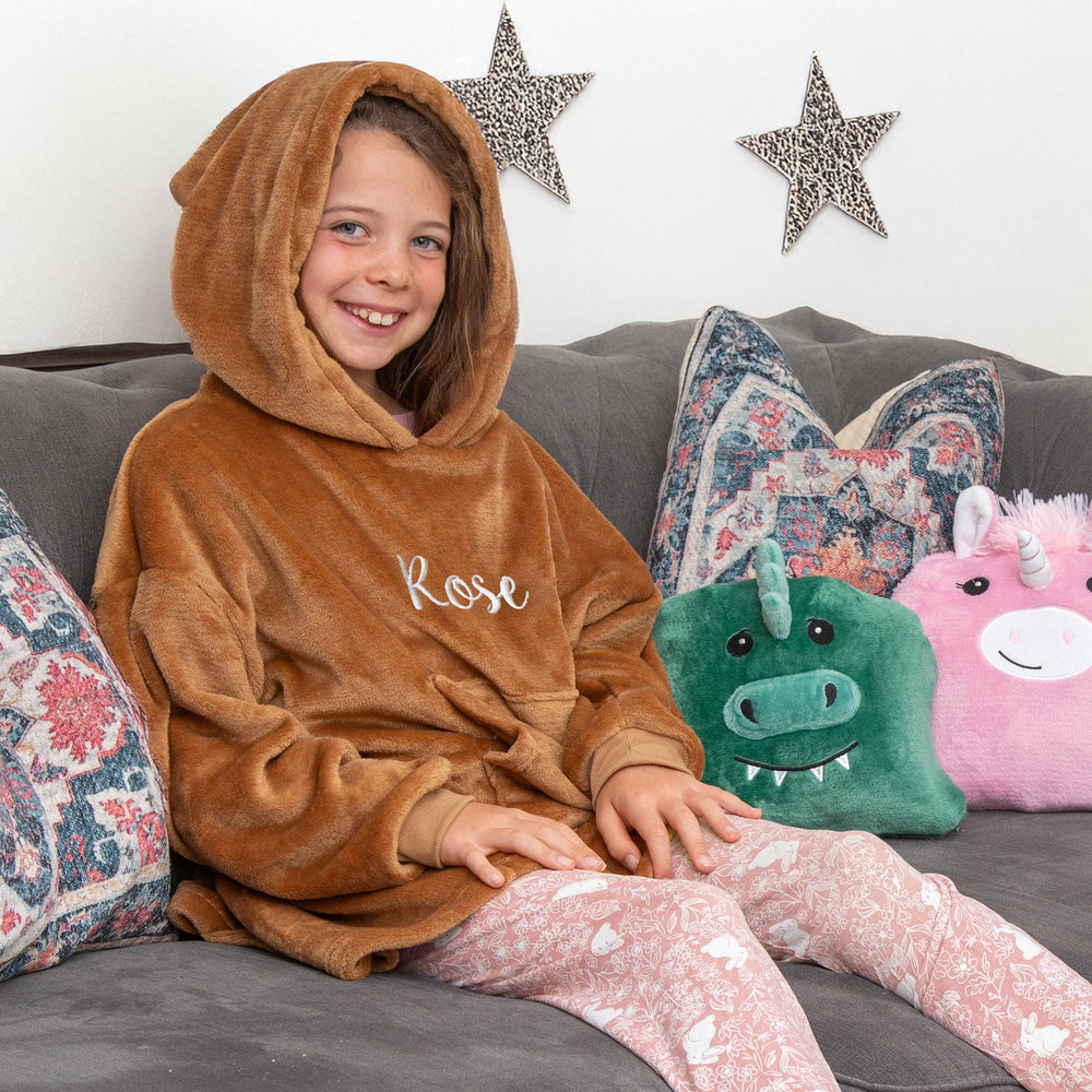 lifestyle image of a girl wearing a teddy bear hoodie and cushion combo