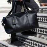 personalised faux leather holdall in black with a debossed luggage tag