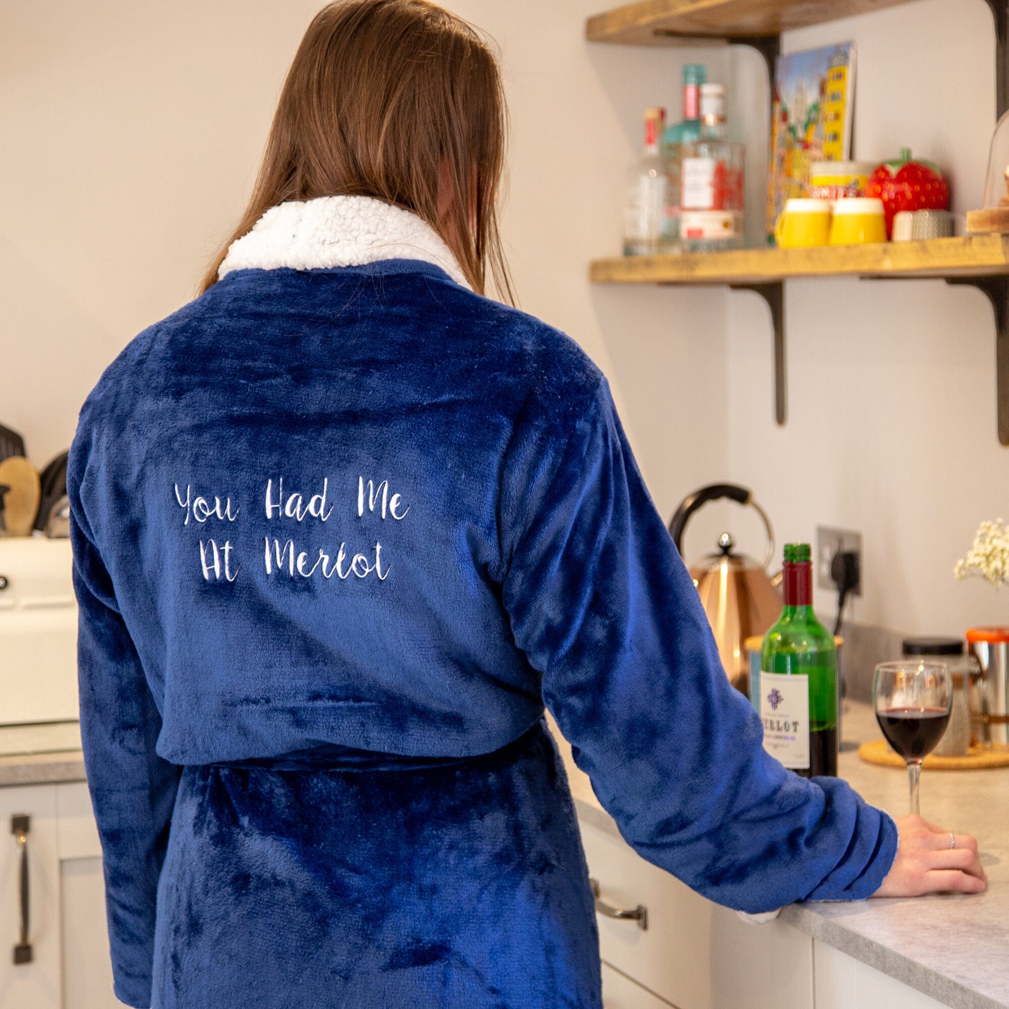Female wearing a personalised navy blue robe with text in a kitchen