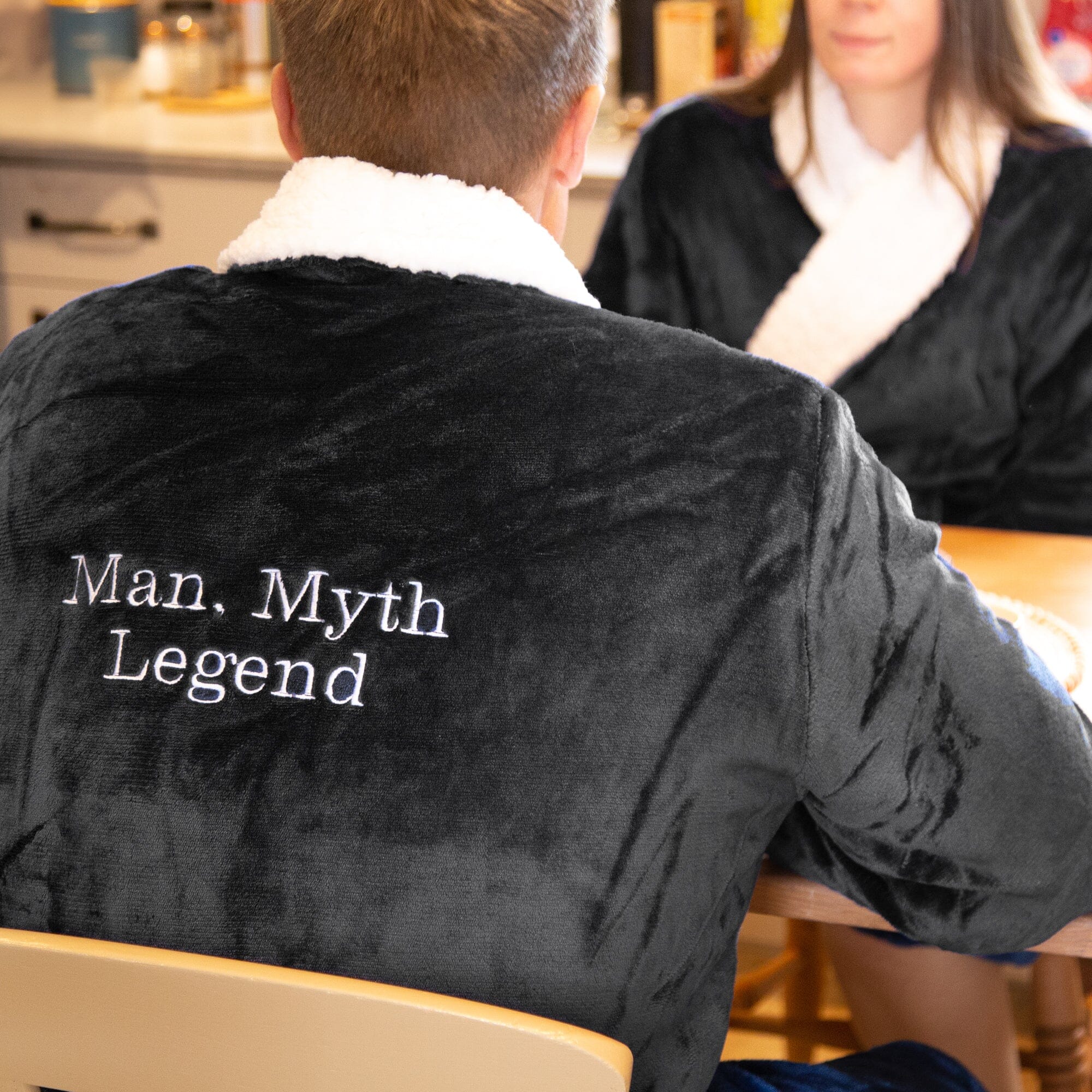 Person wearing a black personalised sherpa robe with 'Man, Myth Legend' text in a casual setting.