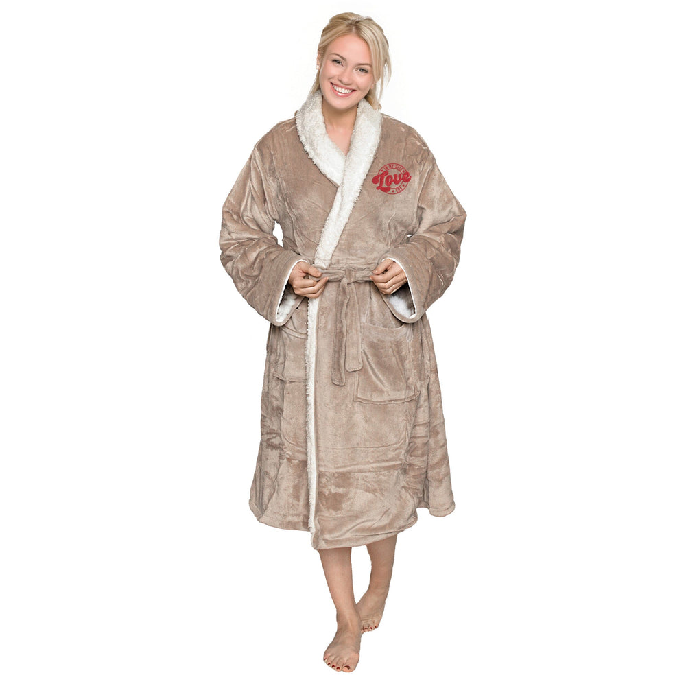 Woman wearing an embroidered Taupe sherpa robe with 'Self Love Era' logo, on a white backdrop