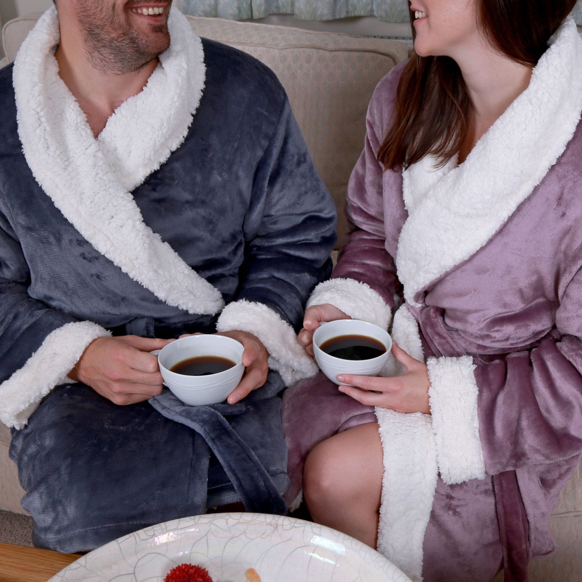 a happy couple sitting with coffe cups and wearing sherpa robes