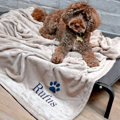 Natural coloured dog blanket with Rufus embroidered underneath a paw print. Rufus is enjoying the blanket.