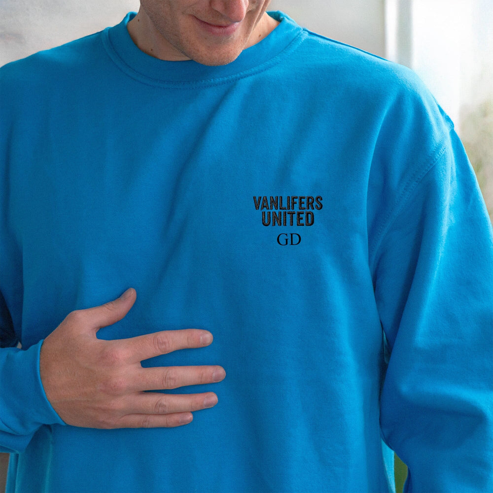 A close-up of a person wearing a bright blue crewneck sweatshirt with black text on the left chest reading 'VANLIFERS UNITED' and 'GD'.