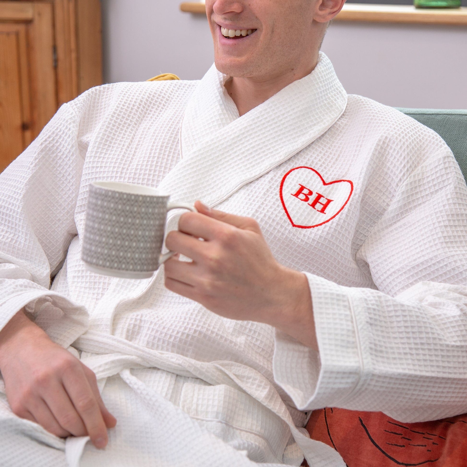 a man sitting on a couch wearing a Personalised Waffle Style Monogrammed Robe with a heart monogram with initials