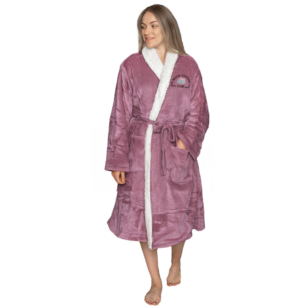 Woman wearing an embroidered lavender sherpa robe with a 'Book Lovers Club' logo, on a white backdrop