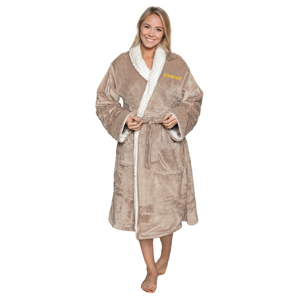 Woman wearing a sherpa taupe robe with embroidered sparkle zodiac name, white lining on a white background