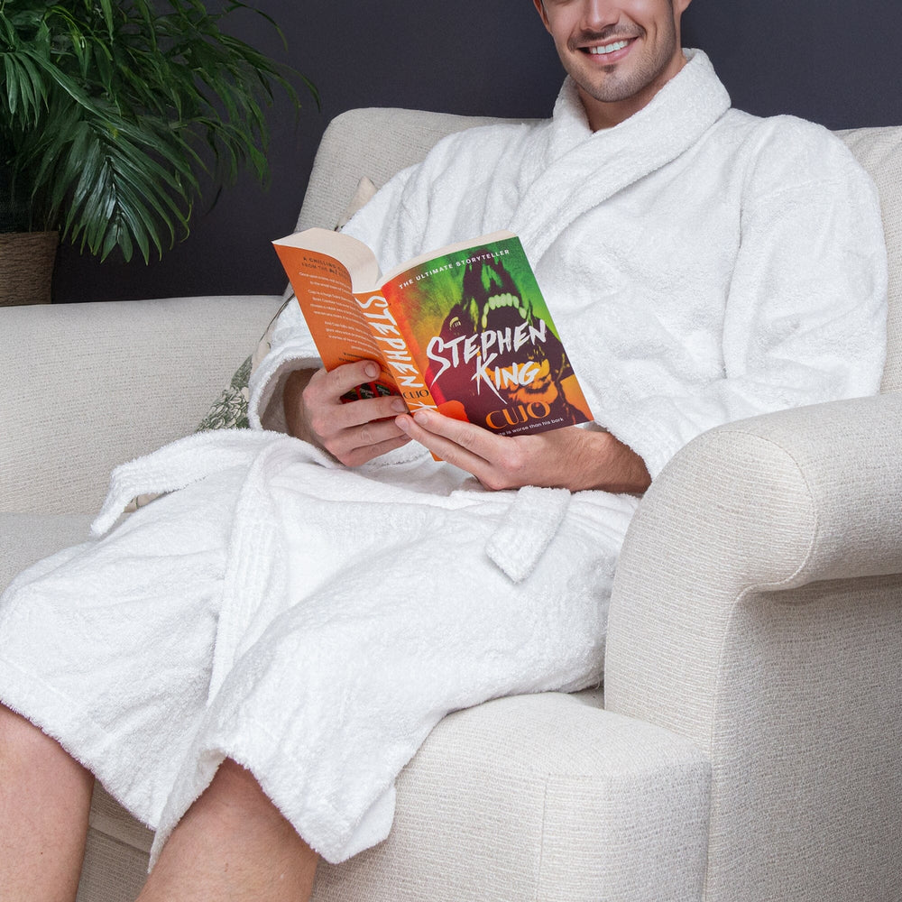 man wearing a white dressing gown reading a book