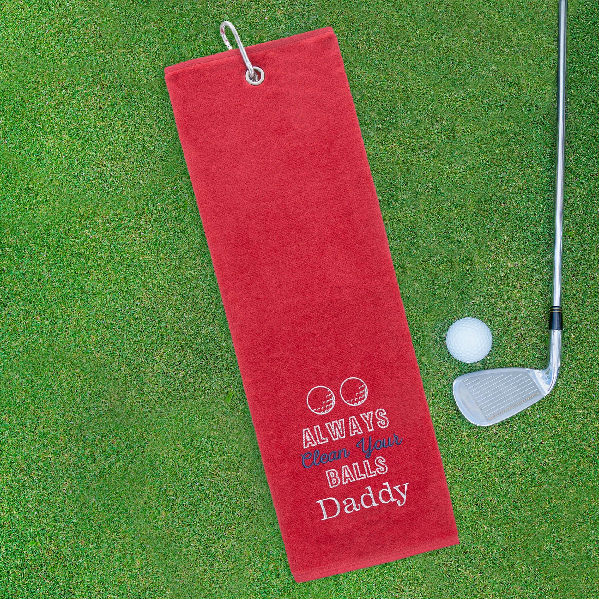 Red golf towel with humorous text on a green grass background