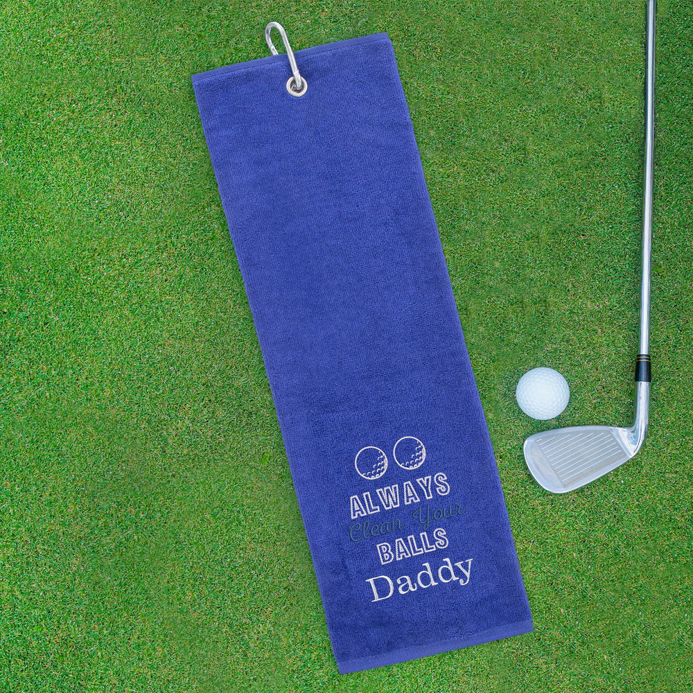 Blue golf towel with humorous text on a green grass background with golf club and ball.
