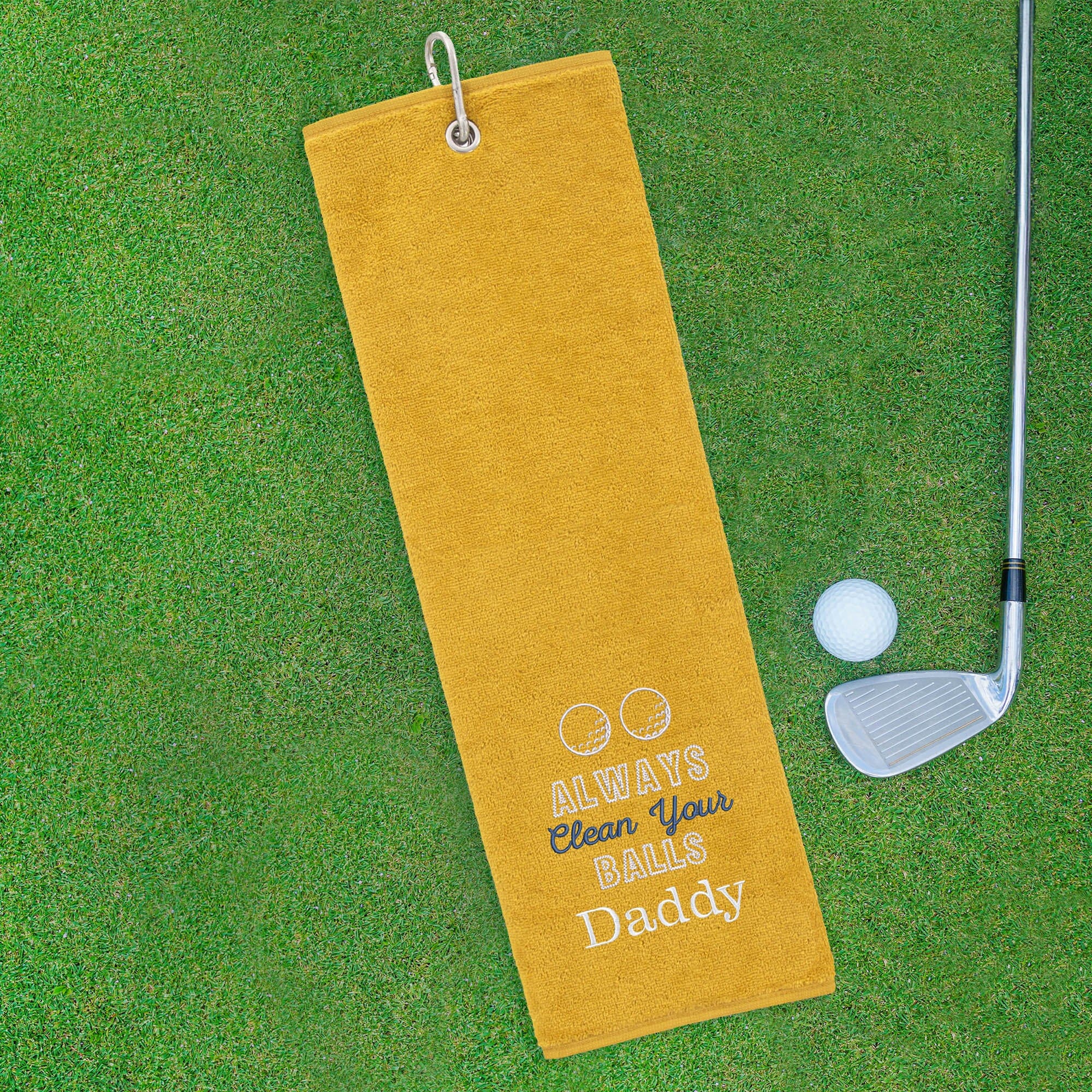 Yellow golf towel with humorous text on a green golf course