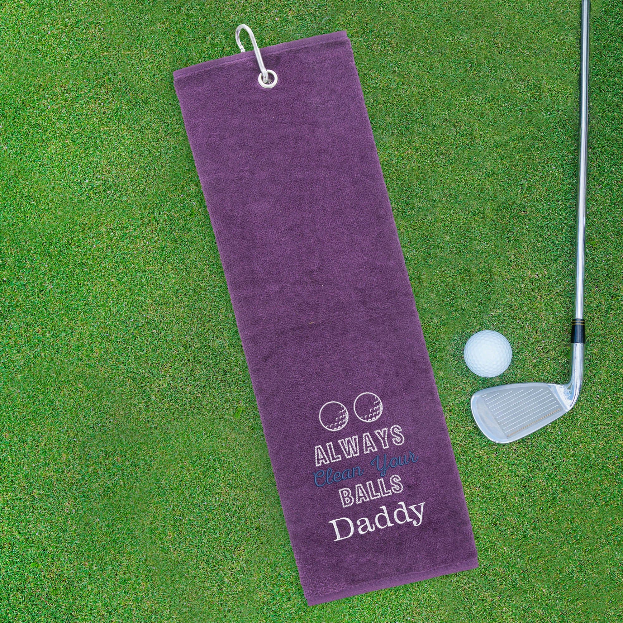 Purple golf towel with text on a green grass background