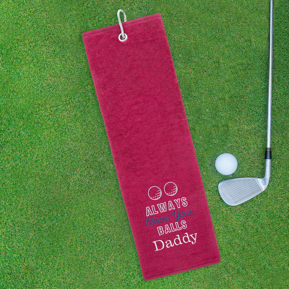 Red golf towel with humorous text on a green grass background
