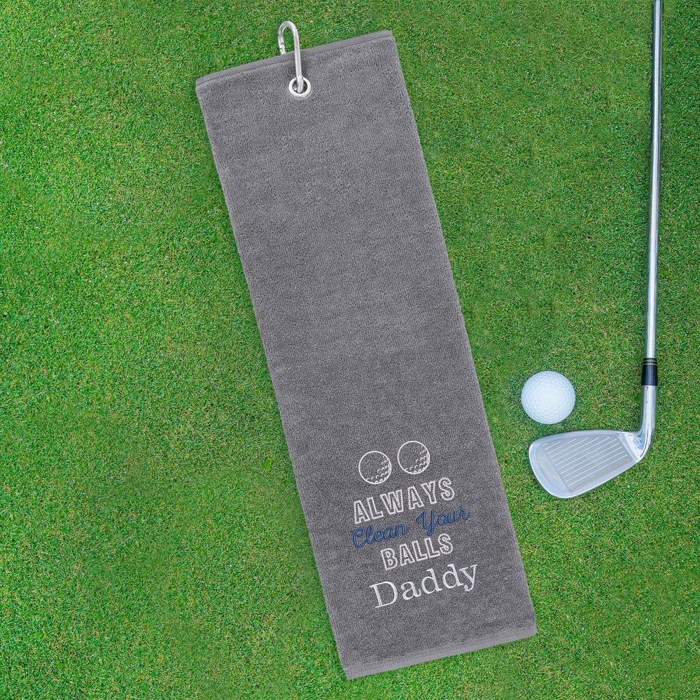Gray golf towel with humorous text on a green grass background
