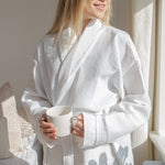 woman wearing a white waffle bathrobe gripping a mug
