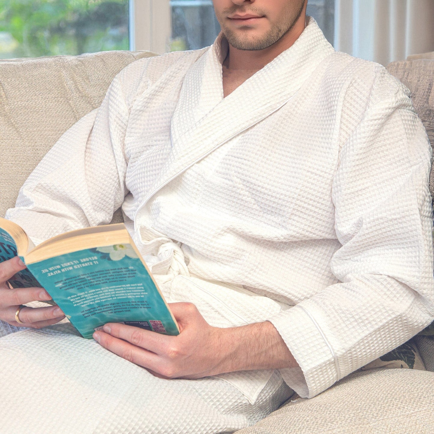 man reading a book in a white waffle bathrobe