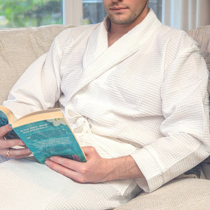 man reading a book in a white waffle bathrobe