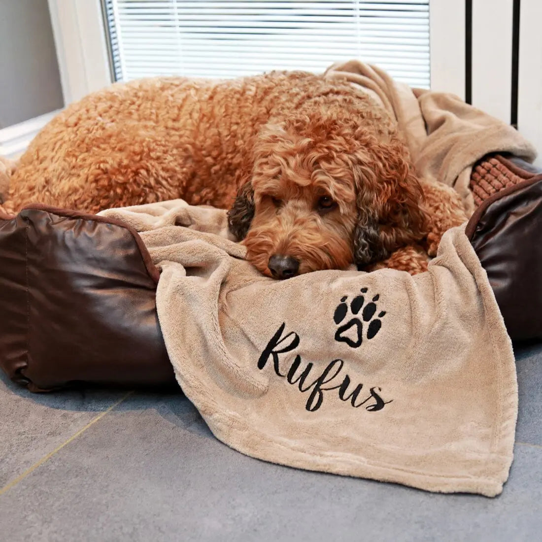 Personalised Dog Blanket with Rufus and a Paw Logo Embroidered on, Rufus snuggled up with the blanket on this bed