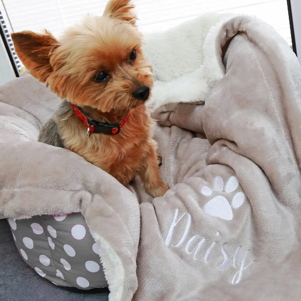 Taupe-coloured Personalised Mini Sherpa Dog blanket with Daisy embroidered underneath a paw print. Lifestyle shot on a dog bed